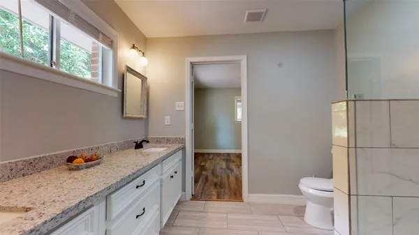 a spacious bathroom with a granite countertop sink toilet and mirror