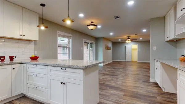 a kitchen with white cabinets and wooden floor