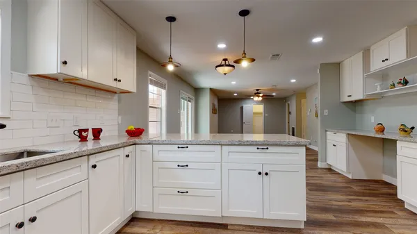 a kitchen with white cabinets and chandelier