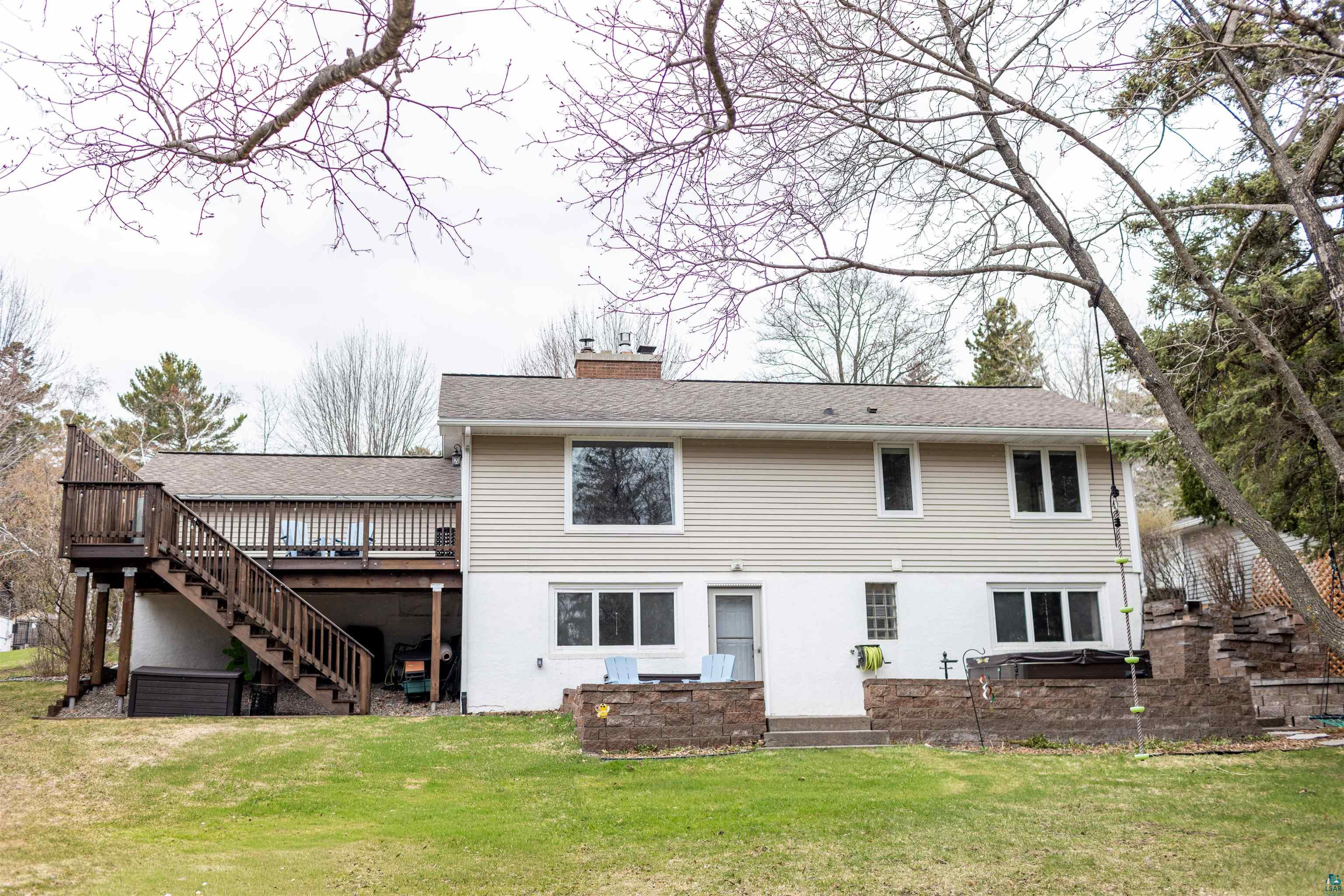 3704 Greysolon Road Duluth, MN 55804 - Photo 42 of 51 Rear exterior featuring a multi-level wood deck with stairs, a patio, and a grass lawn