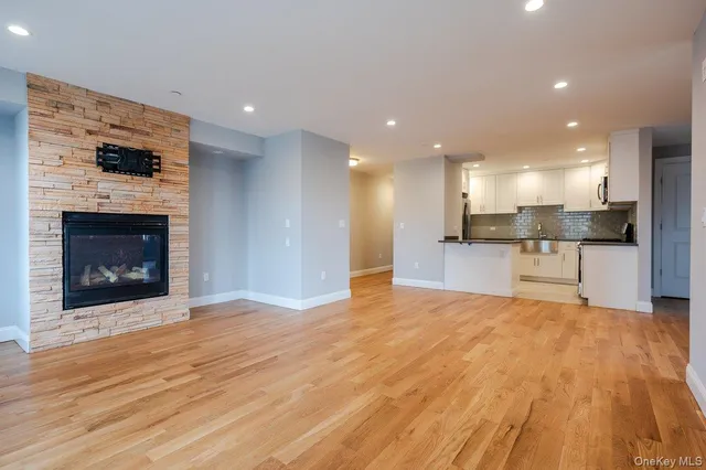 a view of an empty room with kitchen and fireplace