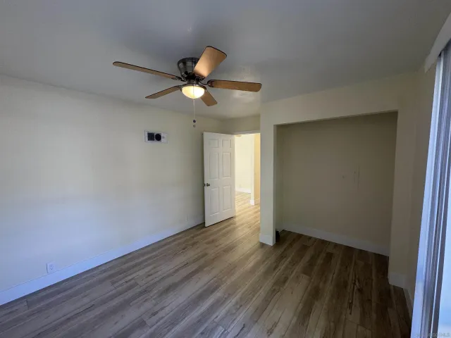 an empty room with wooden floor and a ceiling fan