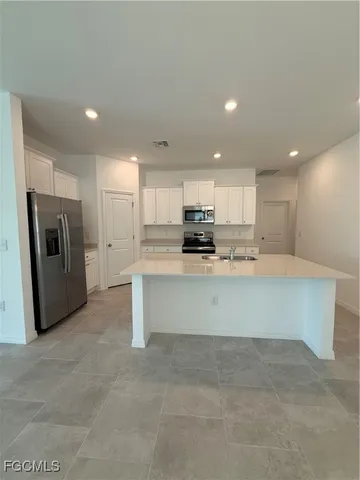 a large white kitchen with refrigerator a stove a microwave and a sink