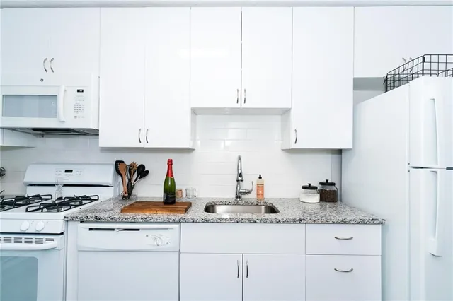 a kitchen with granite countertop white cabinets and white appliances