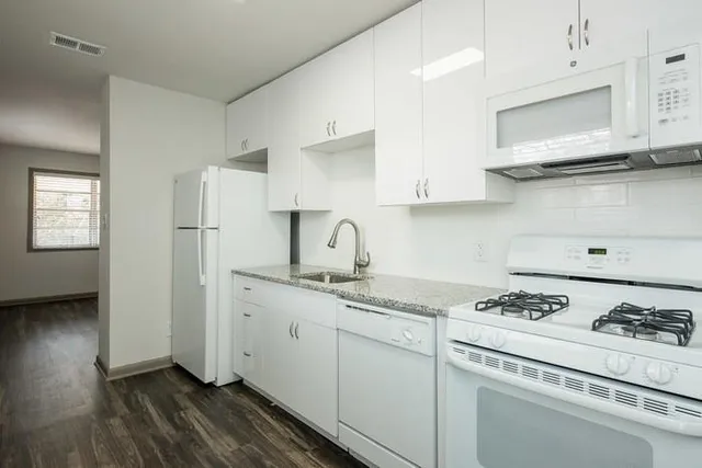 a kitchen with stainless steel appliances granite countertop a sink stove refrigerator and cabinets