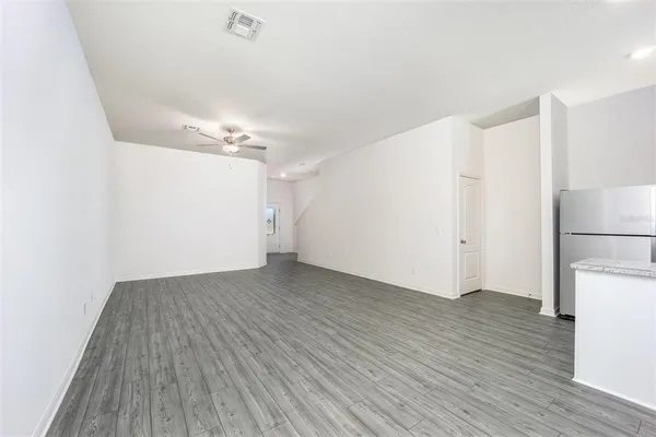 a view of a room with wooden floor and a refrigerator
