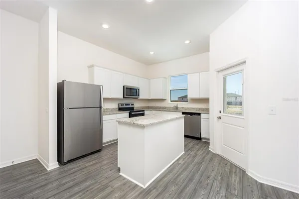 a kitchen with a refrigerator a sink dishwasher and a stove with wooden floor