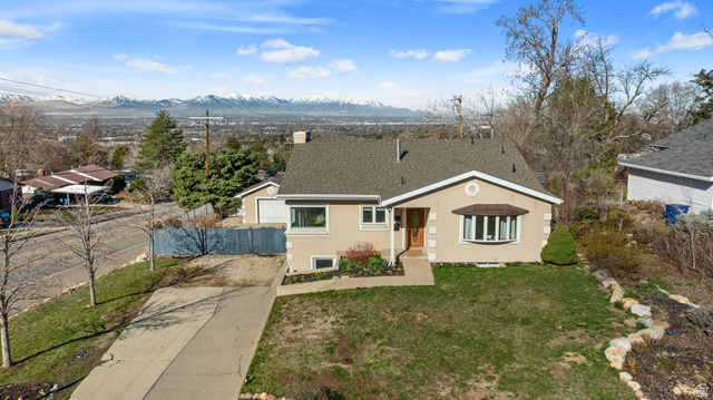 4426 South 3035 East Holladay, UT 84124 - Photo 39 of 49 View of front of house with stucco siding, concrete driveway, a mountain view, roof with shingles, and a chimney