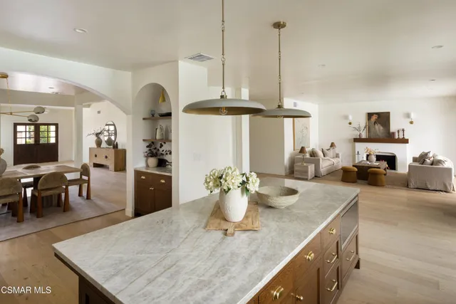 a kitchen with stainless steel appliances kitchen island granite countertop a table chairs and white cabinets
