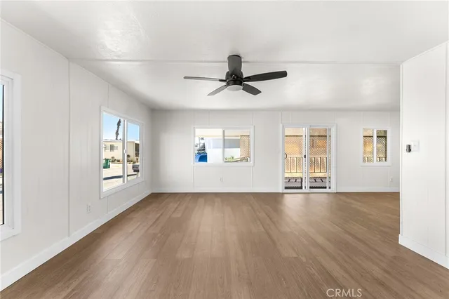 a view of an empty room with a window and wooden floor