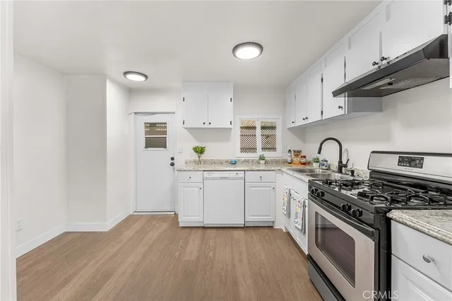 a kitchen with granite countertop a stove top oven sink and cabinets