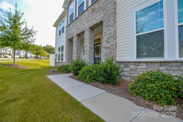 a view of a brick house with a yard and potted plants