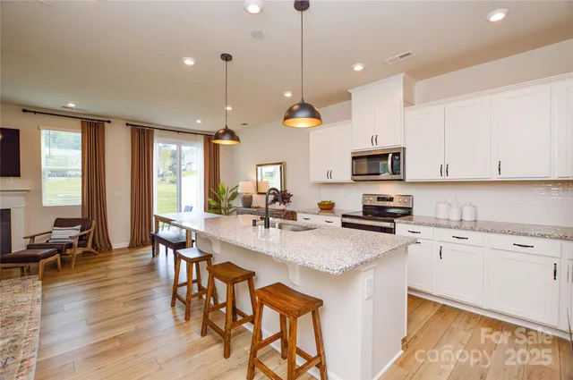 a kitchen with stainless steel appliances kitchen island granite countertop a stove a sink a dining table and chairs with wooden floor