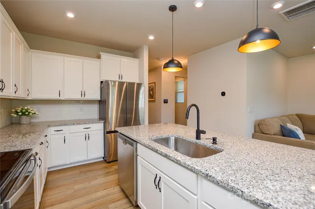 a kitchen with stainless steel appliances granite countertop a sink a stove and a refrigerator