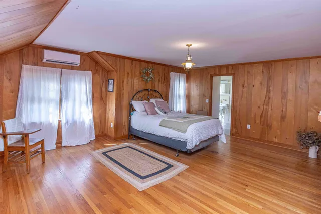 a spacious bedroom with a bed and wooden floor