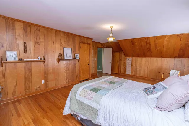 a bedroom with a bed and a lamp with wooden floor