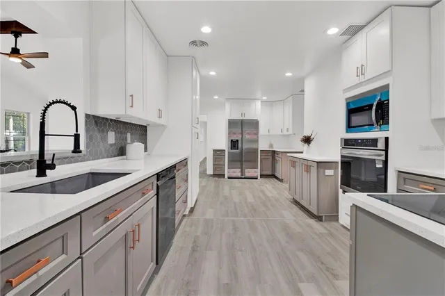 a large kitchen with stainless steel appliances granite countertop a sink cabinets and wooden floor