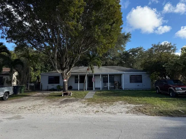a view of a house with a yard and large tree