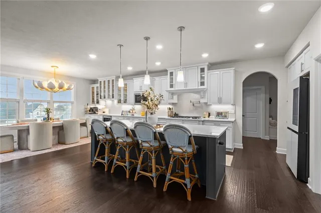 a dining room with stainless steel appliances kitchen island granite countertop a table chairs and a refrigerator