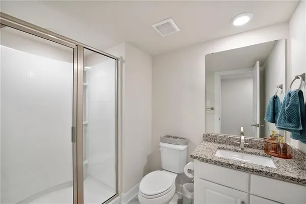 a bathroom with a granite countertop sink toilet mirror and shower