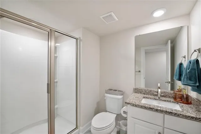 a bathroom with a granite countertop sink toilet mirror and shower