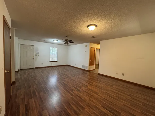 a view of an empty room with wooden floor and a window