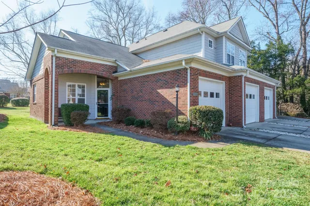 a view of a house with brick walls and a yard with plants