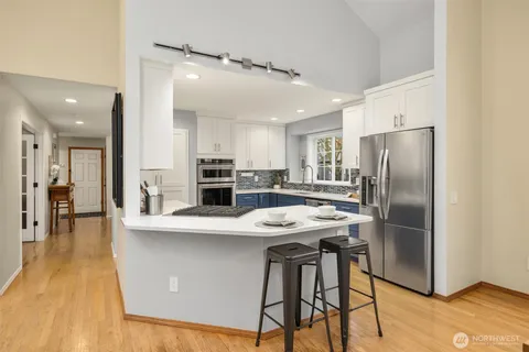 a kitchen with stainless steel appliances granite countertop a dining table chairs refrigerator and microwave