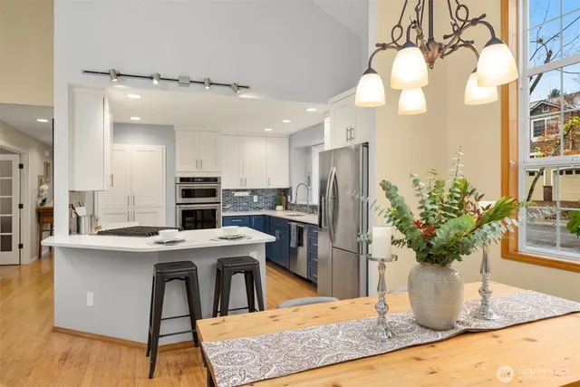 a kitchen with stainless steel appliances kitchen island granite countertop a table chairs in it and wooden floors