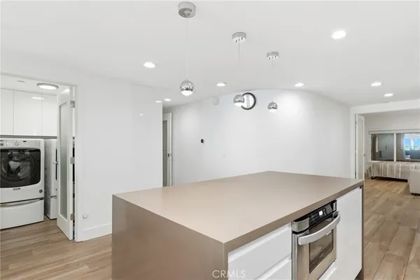 a kitchen with a stove a refrigerator and a dining table with wooden floor