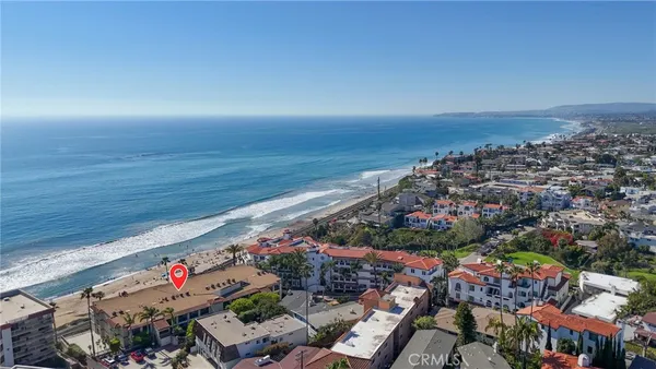 an aerial view of ocean and residential houses with outdoor space