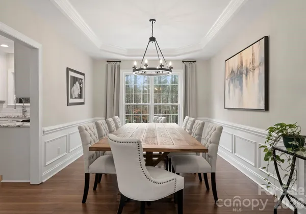 a kitchen with stainless steel appliances granite countertop a dining table chairs stove and white cabinets