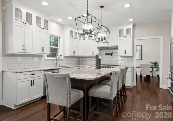 a kitchen with stainless steel appliances granite countertop a sink dishwasher a stove top oven a large island with the island a oven and cabinets