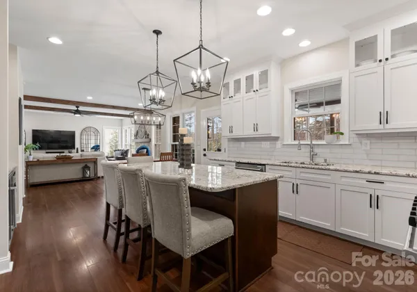 a kitchen with kitchen island granite countertop a stove a sink dishwasher a dining table and chairs with wooden floor