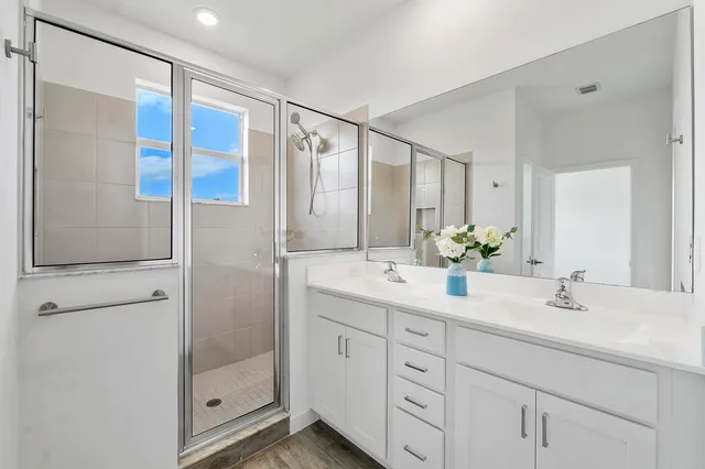 a bathroom with a double vanity sink mirror and shower