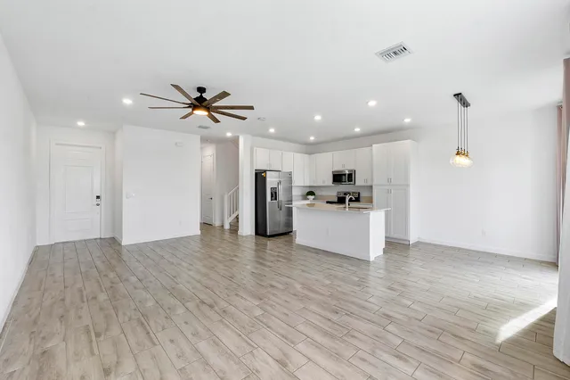 a view of a livingroom with a ceiling fan wooden floor and a ceiling fan