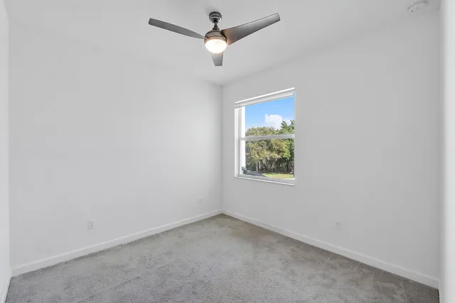 an empty room with a window and a fan