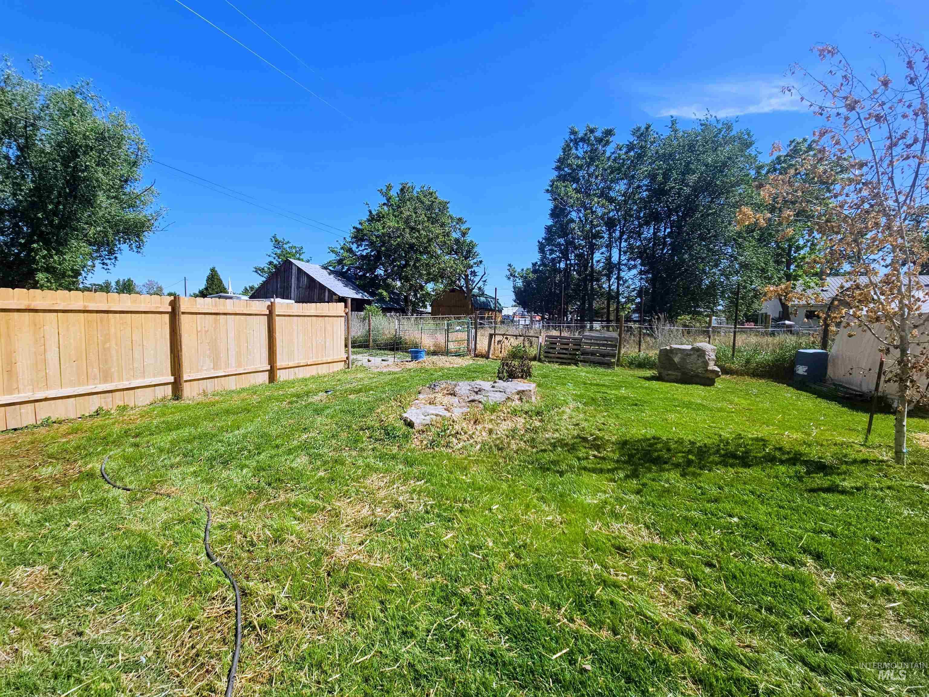 8392 Main Street Letha, ID 83636 - Photo 26 of 31 Expansive grassy yard featuring a new privacy fence, mature trees, and open-air storage