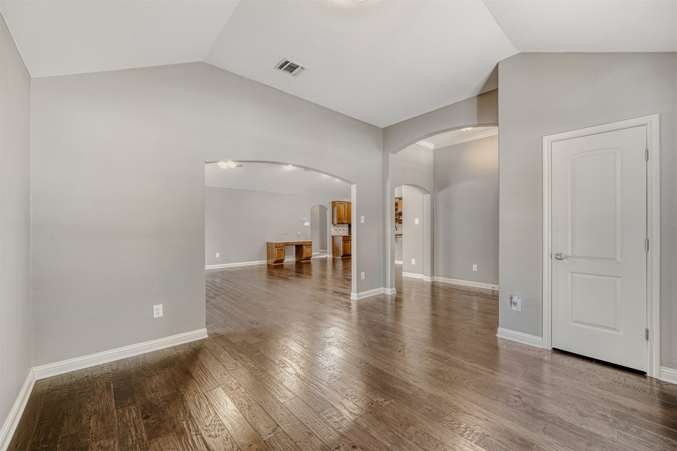 2431 Santa Barbara Loop Round Rock, TX 78665 - Photo 16 of 34 Unfurnished living room with vaulted ceiling, hardwood / wood-style floors, and arched walkways