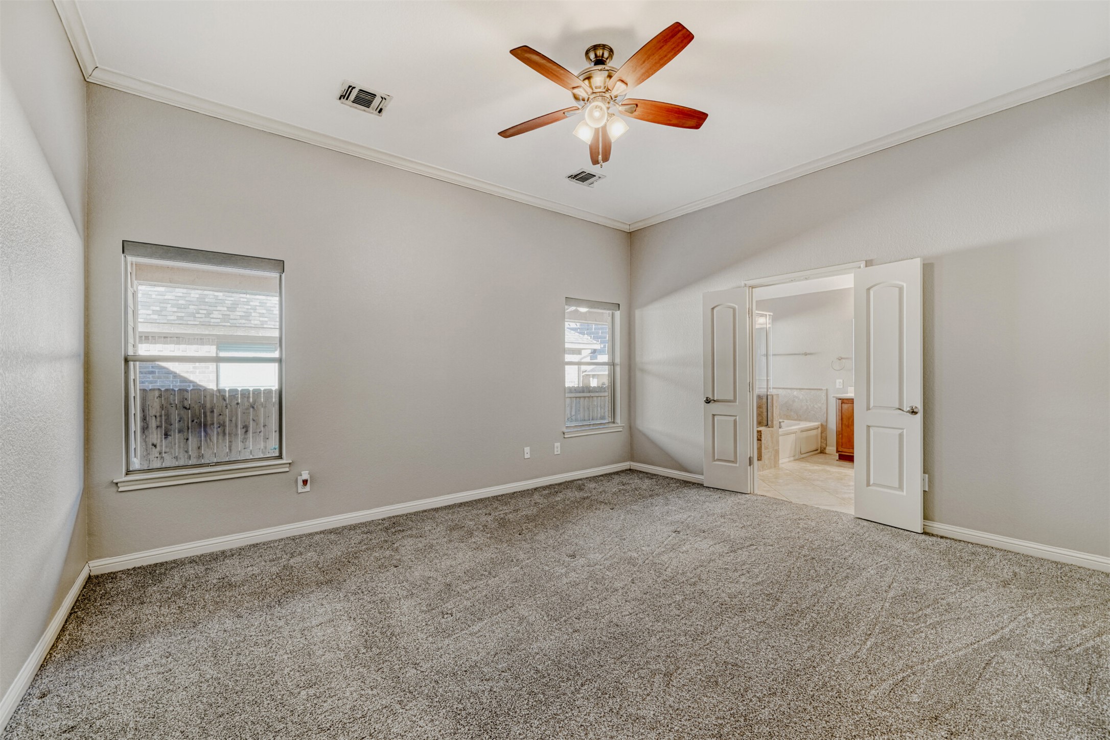 2431 Santa Barbara Loop Round Rock, TX 78665 - Photo 18 of 34 Unfurnished bedroom featuring crown molding, light colored carpet, a ceiling fan, and ensuite bath