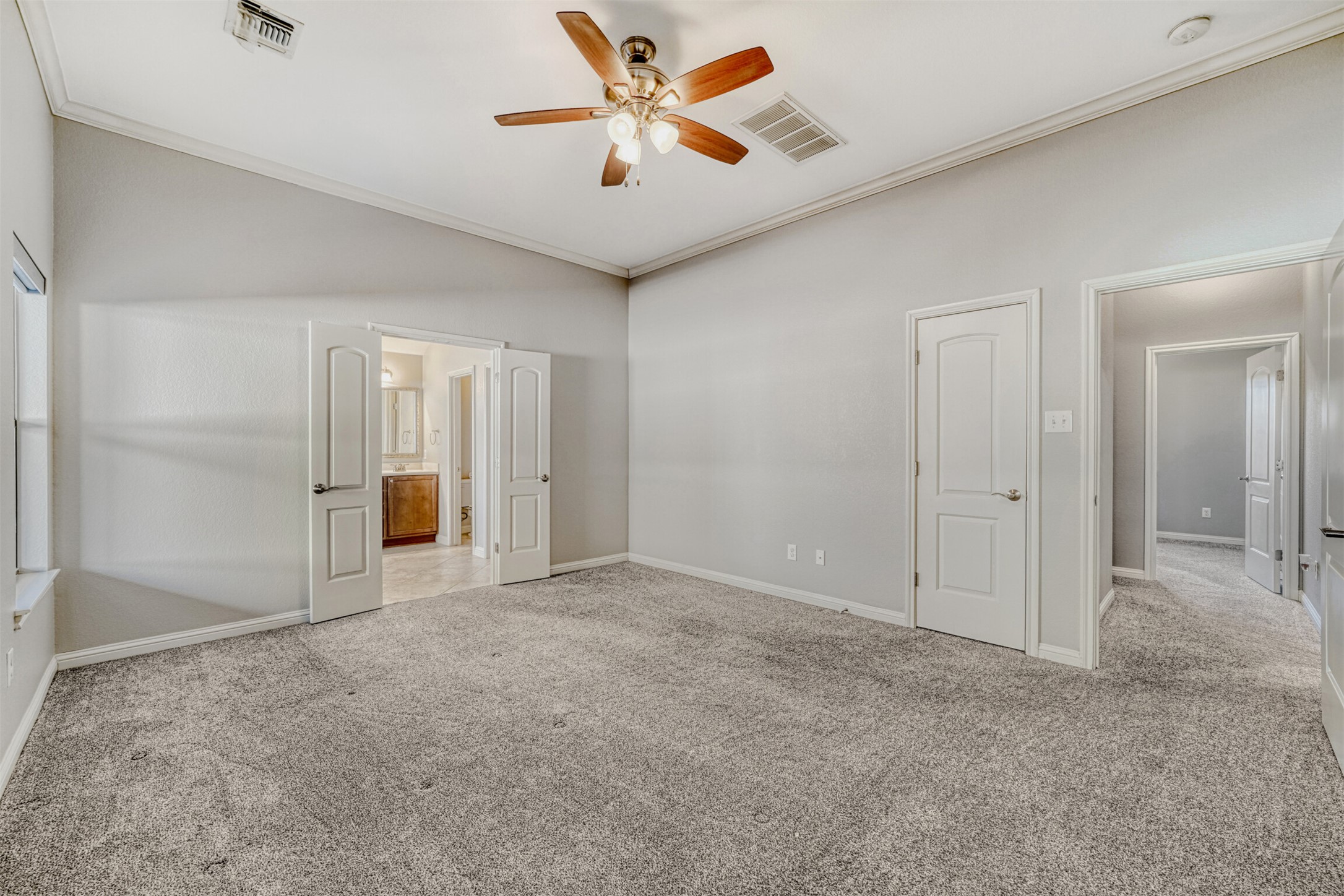 2431 Santa Barbara Loop Round Rock, TX 78665 - Photo 20 of 34 Unfurnished bedroom with ornamental molding, light carpet, a ceiling fan, and ensuite bath
