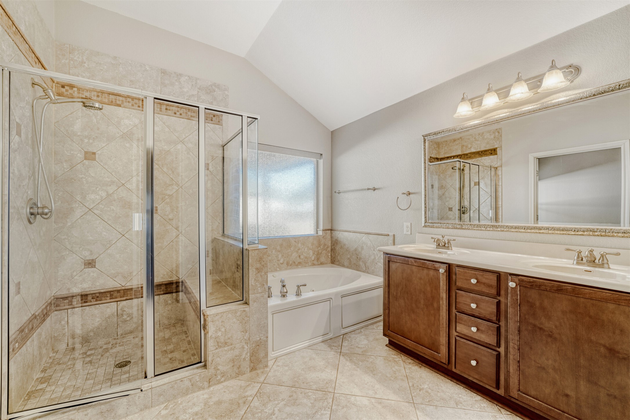 2431 Santa Barbara Loop Round Rock, TX 78665 - Photo 22 of 34 Bathroom featuring a garden tub, double vanity, a shower stall, lofted ceiling, and light tile patterned floors