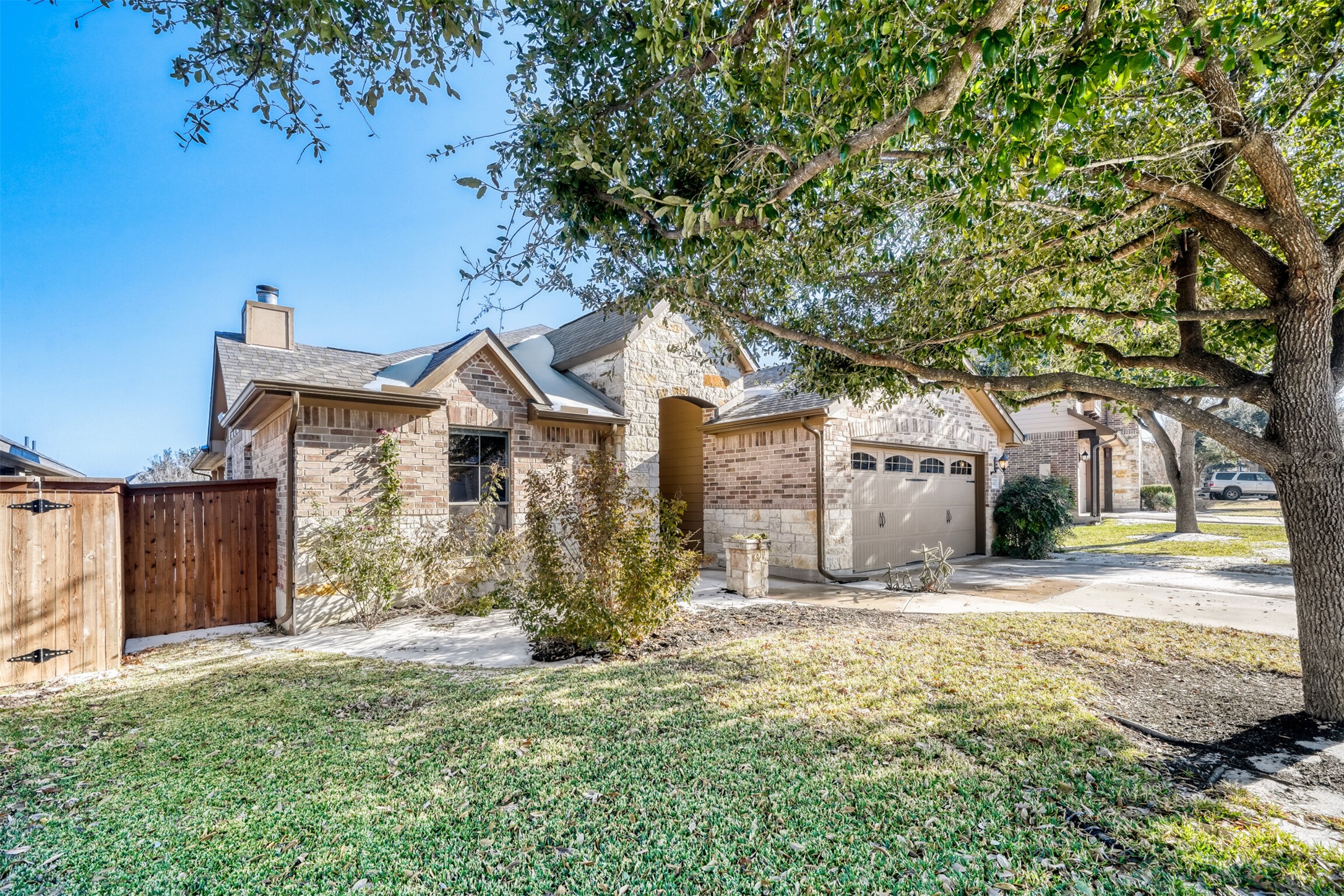 2431 Santa Barbara Loop Round Rock, TX 78665 - Photo 3 of 34 View of front of house with stone siding, concrete driveway, a chimney, a garage, and a gate