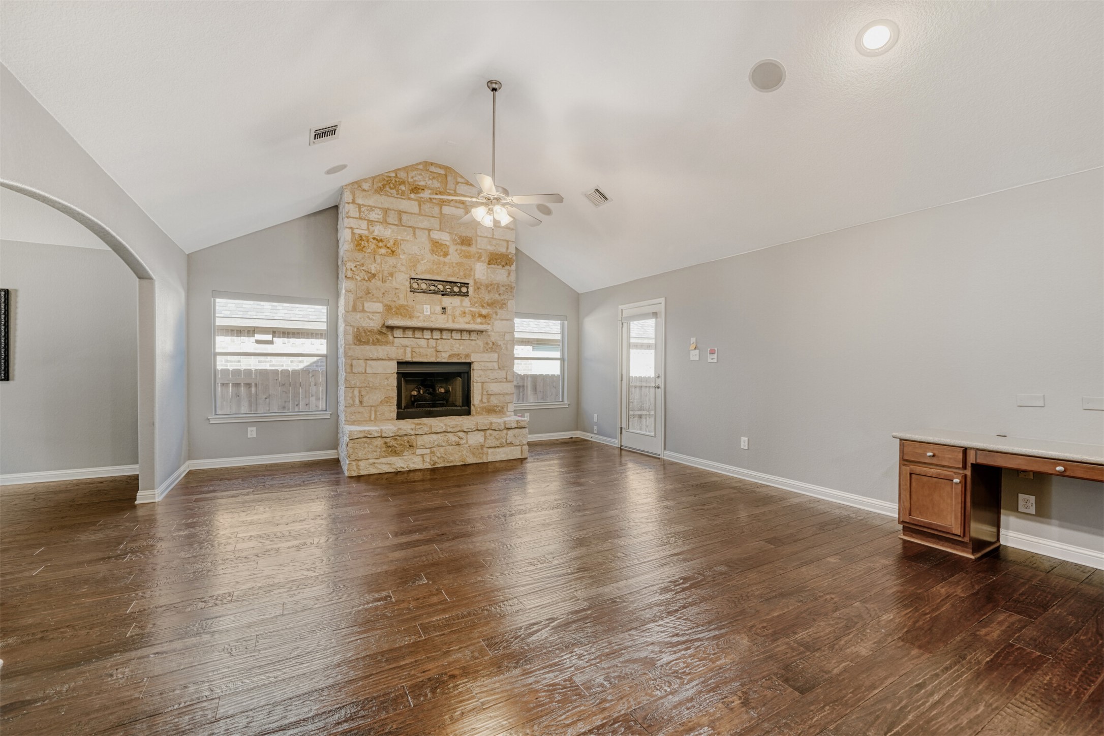 2431 Santa Barbara Loop Round Rock, TX 78665 - Photo 4 of 34 Unfurnished living room with a stone fireplace, healthy amount of natural light, dark wood finished floors, a ceiling fan, and high vaulted ceiling