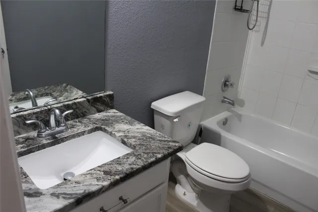 a bathroom with a granite countertop toilet sink and mirror