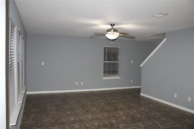 an empty room with windows and ceiling fan