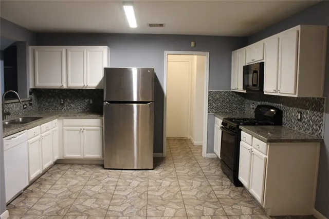 a kitchen with a refrigerator sink and cabinets
