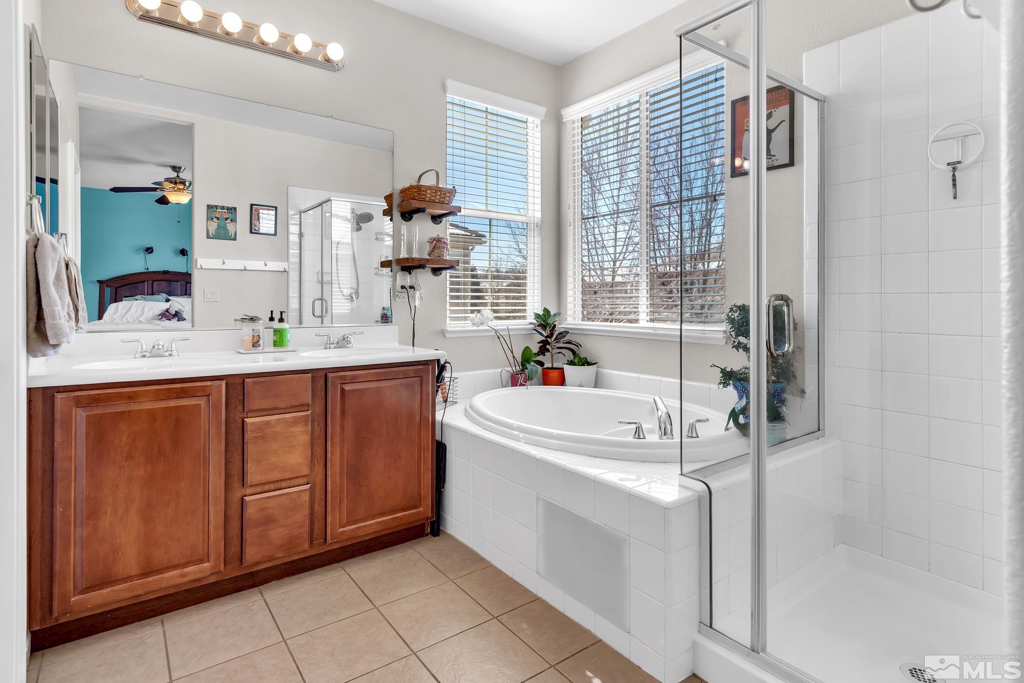 596 Needles Court Reno, NV 89521 - Photo 23 of 40 a bathroom with a double vanity sink a mirror and a bathtub