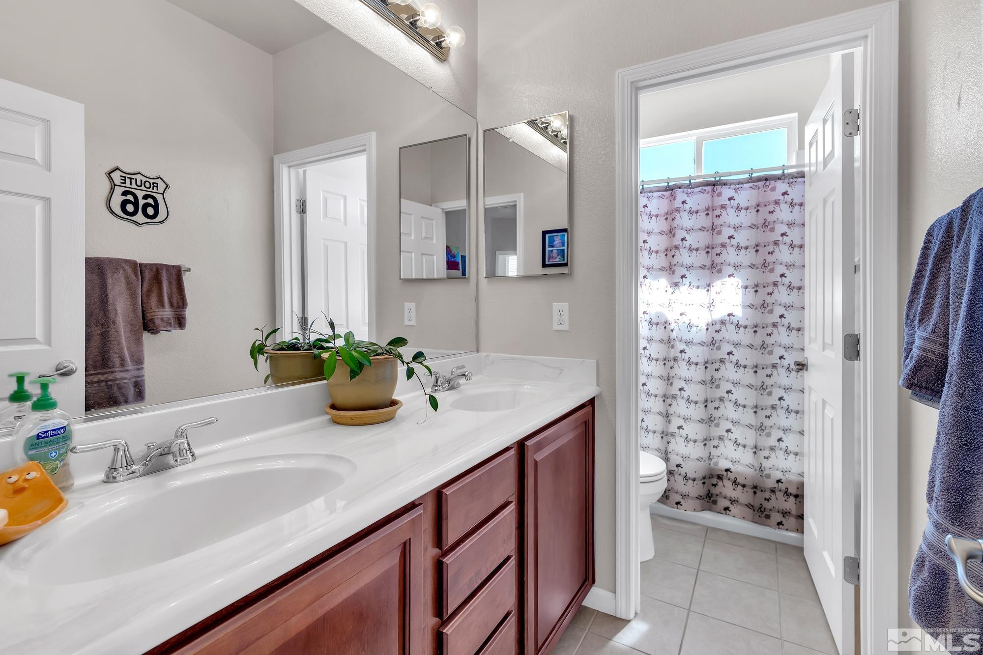 596 Needles Court Reno, NV 89521 - Photo 26 of 40 a bathroom with a granite countertop sink a mirror a vanity and a shower