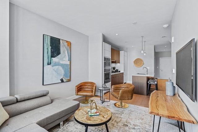 a living room with furniture a rug and kitchen view